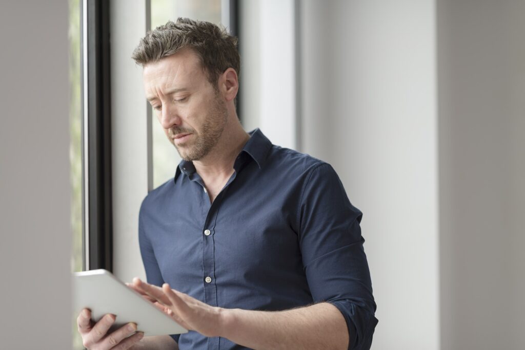 Man using digital tablet by office window