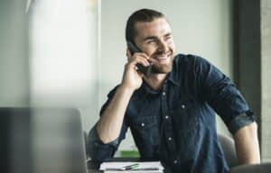 Smiling young businessman on cell phone in office